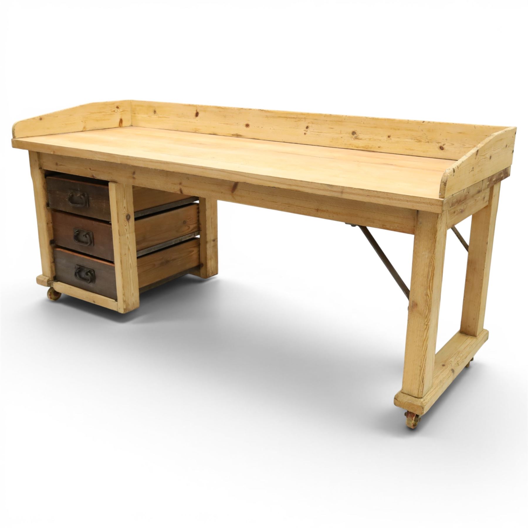 Mid-20th century pitch pine and beech bakers table, three quarter galleried rectangular plank top, three drawer pedestal with iron handles and runners, square supports with iron spandrel, raised on castors 
