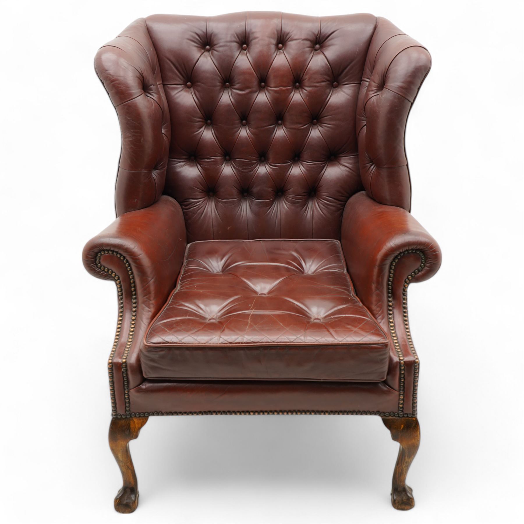 Georgian design leather wingback armchair, deep-buttoned burgundy leather upholstery with rolled arms, studded detail along the edges, raised on cabriole supports terminating in claw and ball feet
