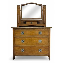 Early 20th century Arts and Crafts oak dressing chest, the arched mirror flanked by floral marquetry inlaid uprights above a shelf and drawer, over three long drawers with square hammered metal plates and circular pulls, on slender supports with castors