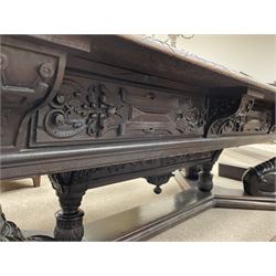 Large 19th century carved oak library table, the rectangular top with lunette carved edge over cartouche panelled and carved  scroll frieze, the central tapering rectangular support relief carved with masks and garlands, on four carved seated lion supports at each corner, on flat angular stretcher with recessed castors stamped ‘Bartholomew & Fletcher, London’
