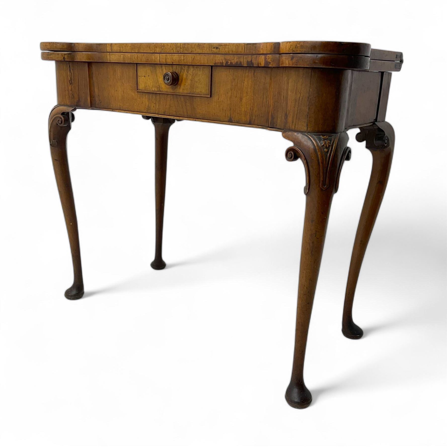 Georgian walnut fold-over card table, shaped rectangular top opening to reveal a baize-lined surface, supported by a concertina pull-out rear mechanism, frieze fitted with single drawer, raised on cabriole supports with foliate carvings terminating in pad feet
