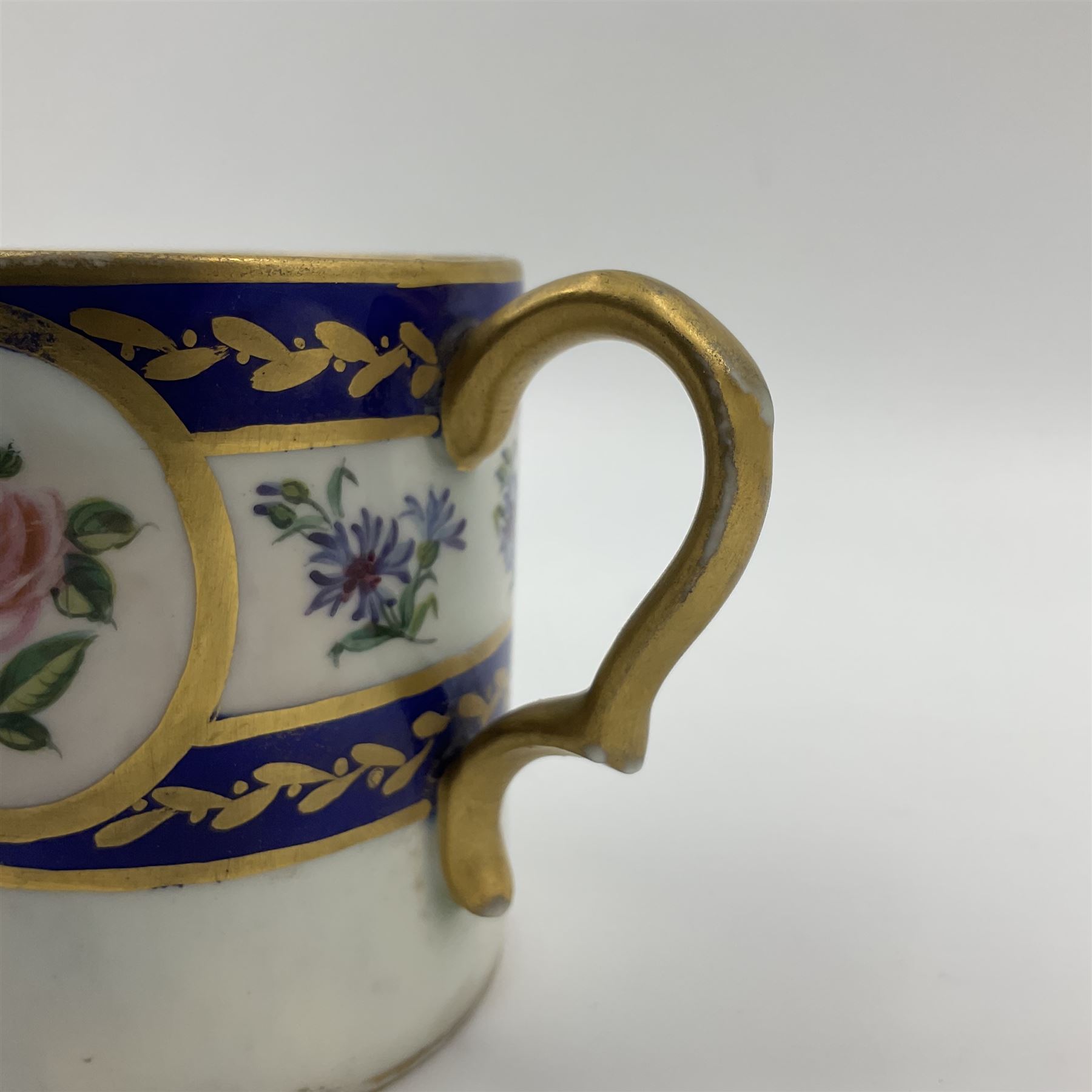 19th Sèvres style porcelain cup and saucer, the cup painted with a figural scene, against a scalloped border of scrolling floral swags on a blue ground, together with a Sèvres soft paste porcelain coffee can and saucer, painted with panels of exotic birds, roses and a border of cornflowers, LL monogram enclosing date letters H above painters mark, coffee can H6.5cm, saucer D13.5cm (2)