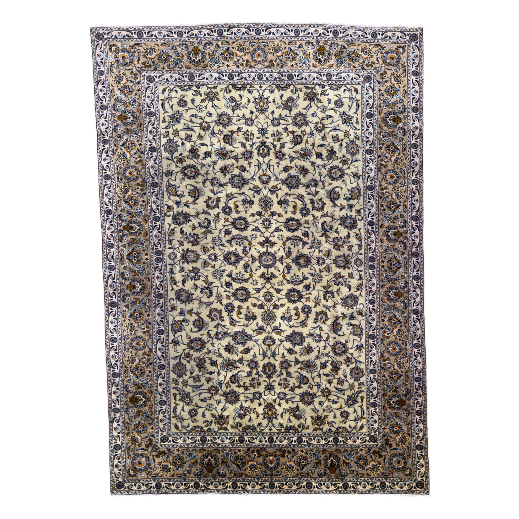 Central Persian Kashan hand-knotted carpet, ivory field with an all-over design of scrolling vines, lotus palmettes, and rosettes in shades of blue, gold, and brown within a blue ground border of palmettes and arabesques between multiple guard stripes