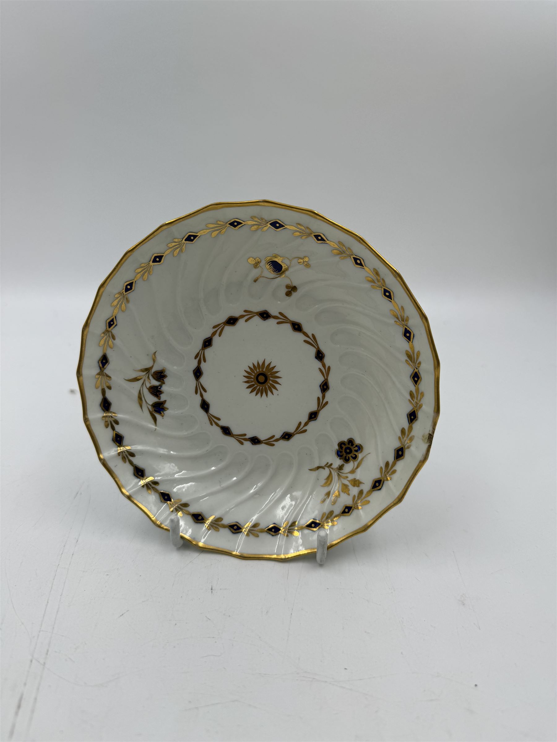 18th century Caughley blue and white sparrow jug, decorated in the Mother and Child pattern, circa 1780-1790, with underglaze C mark beneath, H9cm, together with a Worcester coffee cup, circa 1785 painted with floral sprays in underglaze blue and gilt, with crescent mark beneath, and a Caughley trio of tea cup, tea bowl and saucer, each of moulded wrythen fluted form and decorated with gilt and blue sprigs and bands, each with crescent mark beneath, (5)