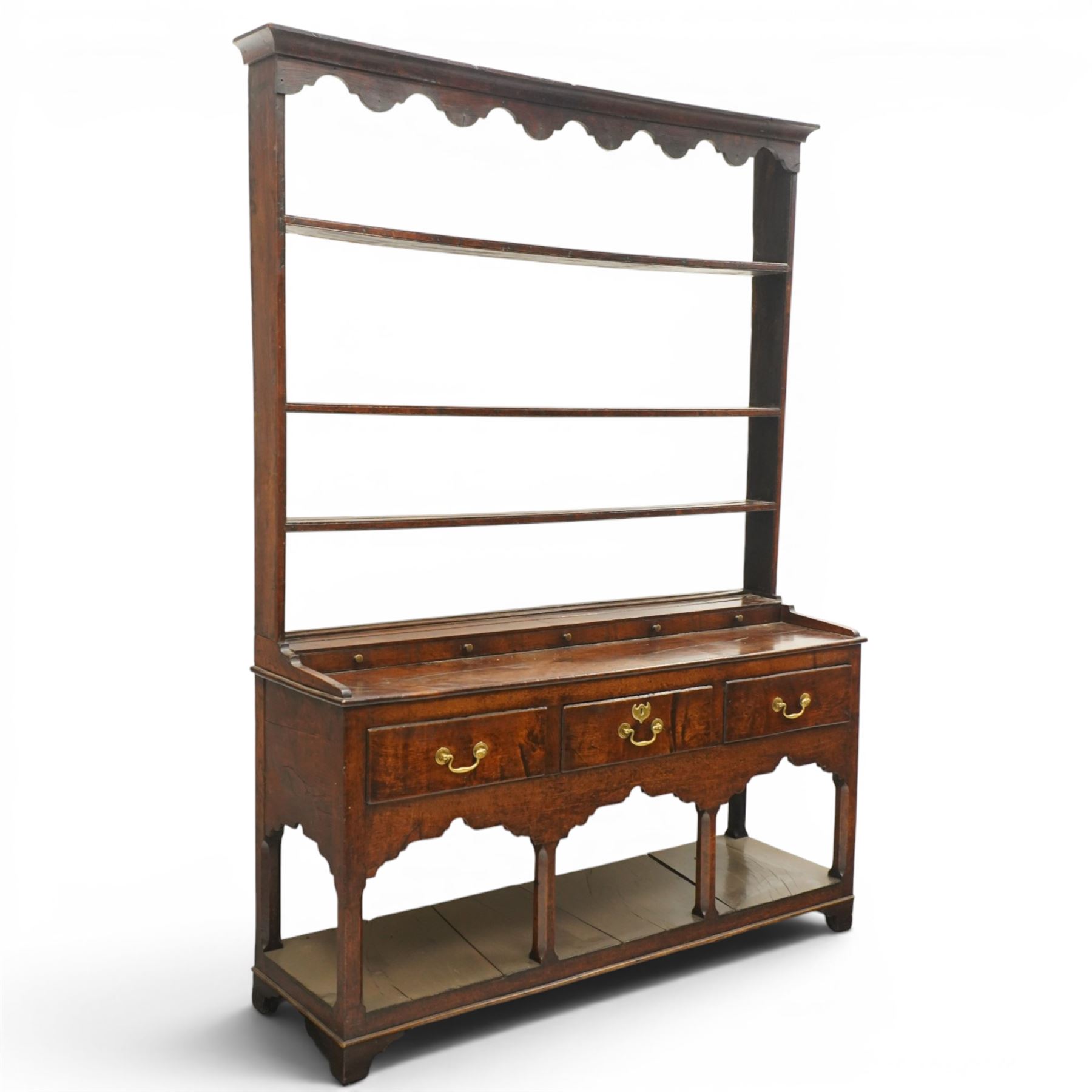 18th century Georgian oak dresser base with plate rack, the three-tier plate rack with shaped frieze, the base with rectangular top with raised back fitted with five spice drawers, over three drawers with brass swan neck handles, raised on six square chamfered supports united by undertier 