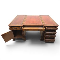 George III style large mahogany reverse breakfront partners desk, red tooled leather writing surfaces crossbanded and moulded edges, flanked by ring-turned cluster columns three frieze drawers with brass swan neck handles, raised on large pedestals with faux drawer fronted cupboard and three graduated drawers, supported on carved ogee feet decorated with C-scrolled and acanthus leaves