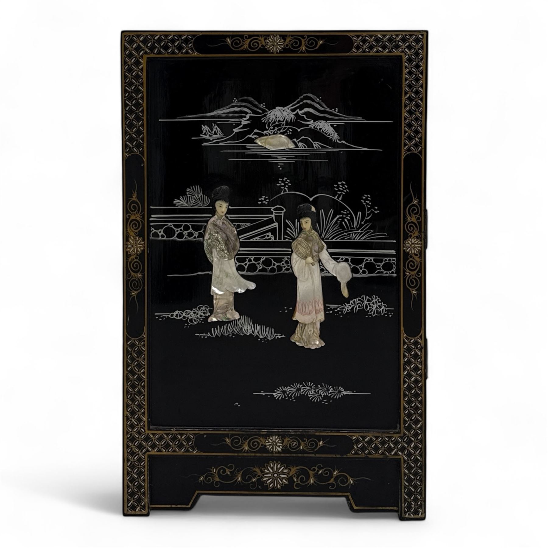 20th century Japanese Shibayama style black lacquered cabinet, rectangular form decorated with mother-of-pearl and hardstone figural inlay, the top with four standing figures, single frieze drawer above two cupboard doors, gilt painted borders and landscape