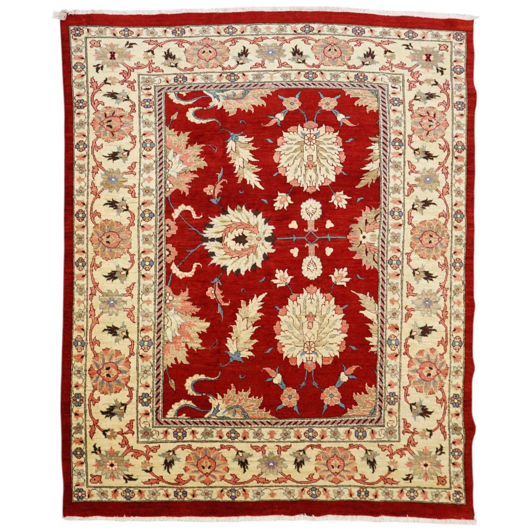 West Persian Sarough hand-knotted carpet, rich madder red field, decorated with stylized palmettes angular vinery and floral sprays within multiple borders of ivory ground and scrolling foliate decoration, with cotton fringe ends 