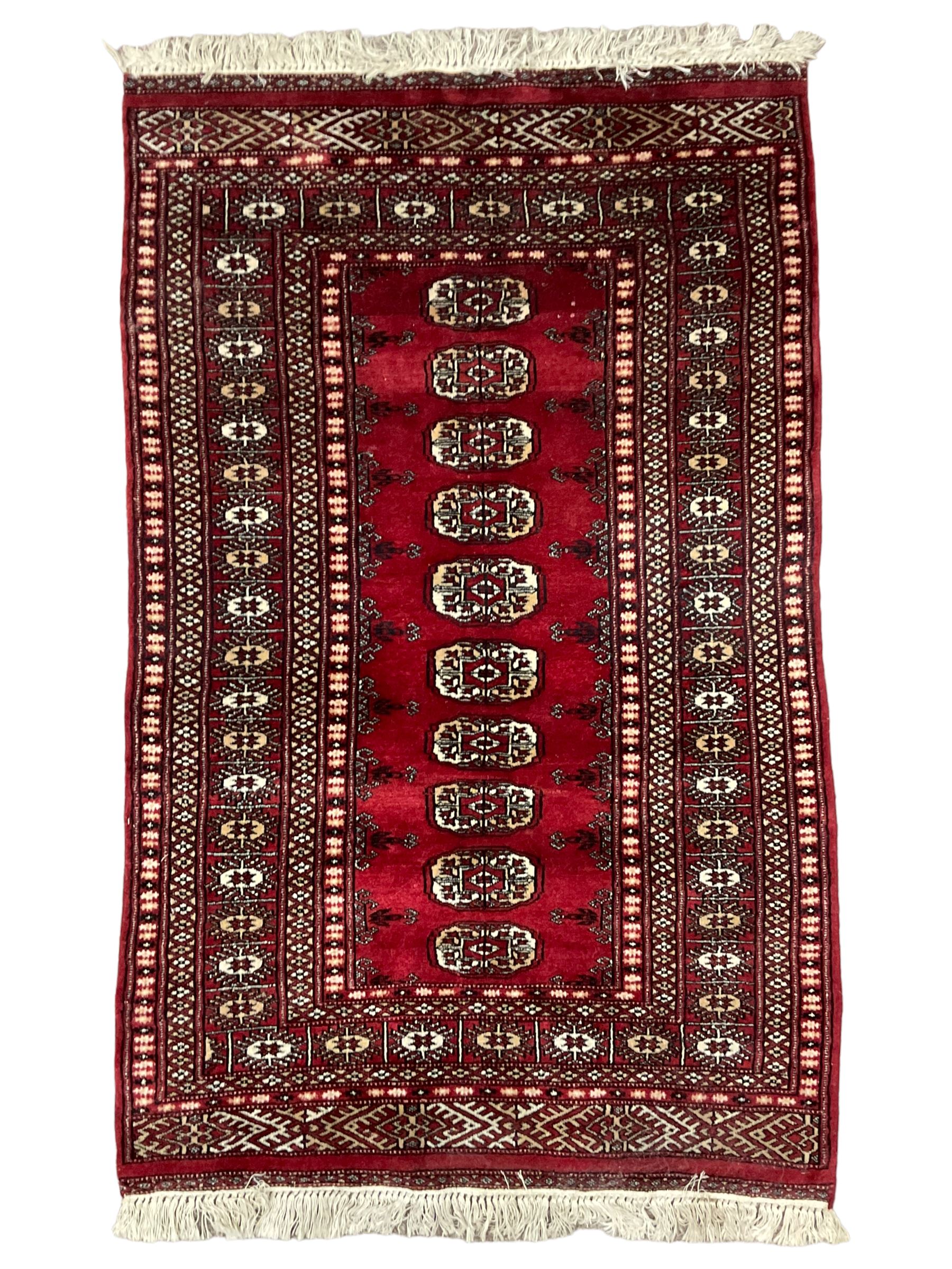 Persian Bokhara rug, red ground and decorated with single row of Gul motifs, multiple band border with geometric design