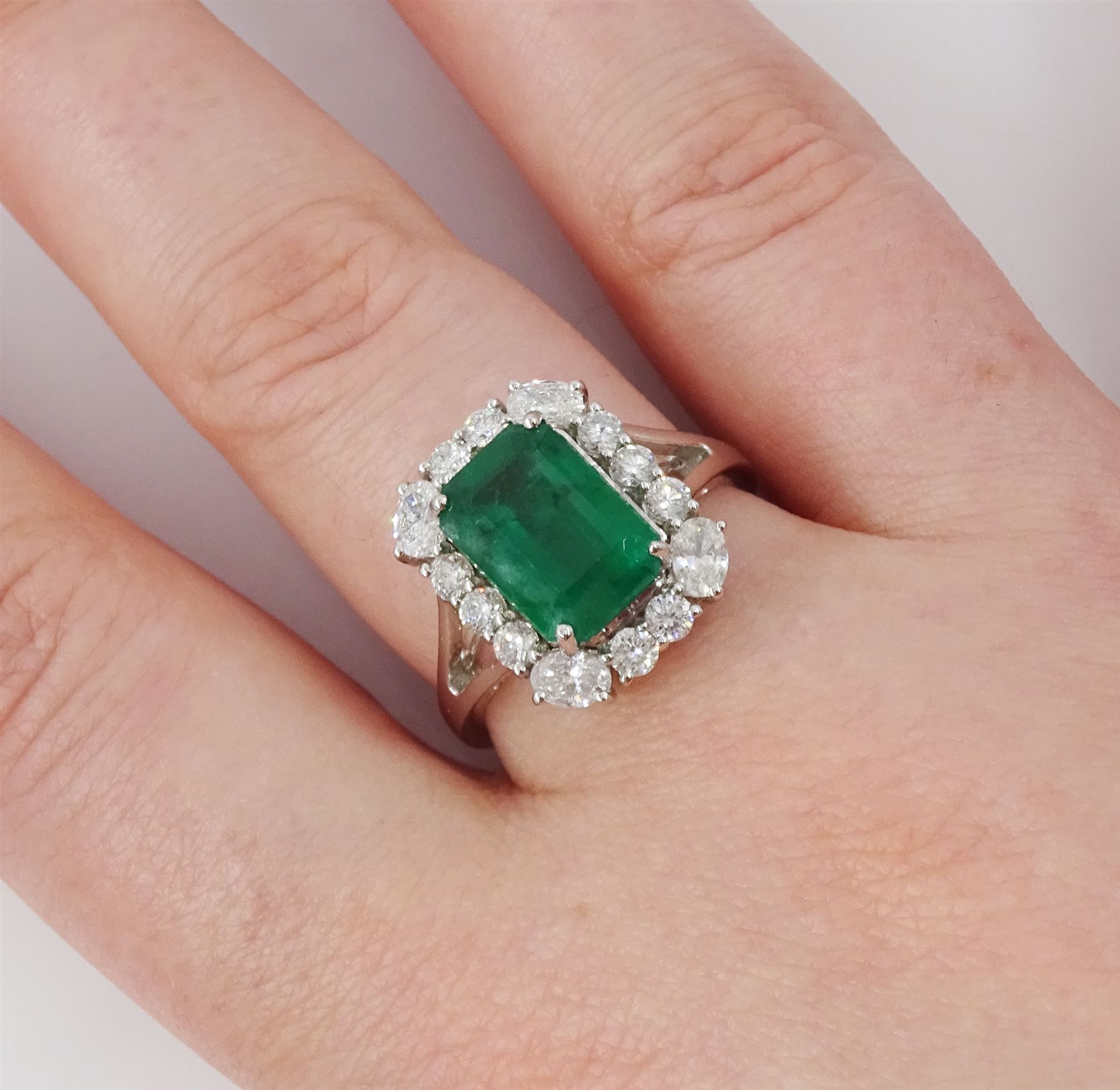 18ct white gold emerald and diamond cluster ring, single octagonal cut emerald of approx 2.90 carat, surrounded by twelve round brilliant cut diamonds and four oval cut diamonds to each corner, stamped 18K, total diamond weight approx 0.90 carat