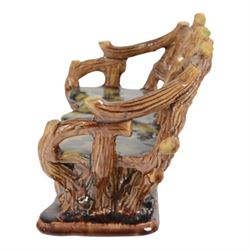 19th century pottery model of a bench, possibly Skey Pottery Tamworth, Staffordshire, the shaped seat mottled in shades of green, dark blue, yellow and brown, supported upon naturalistically modelled tree stumps, the arms and back modelled as intertwined branches, H14cm W21cm D10cm