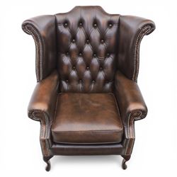 20th century Chesterfield style brown leather wingback armchairs, with button upholstered backs and wings, shaped scroll arms with studded borders, loose seat cushions, raised on cabriole supports with pad feet