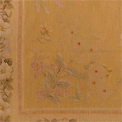 20th-century Aubusson-style woven tapestry of rectangular form with mustard yellow field decorated with scattered floral sprays in soft pastel tones of pink, cream, and muted green, within a narrow guard stripe with an outer border of trailing blossoms and foliage 