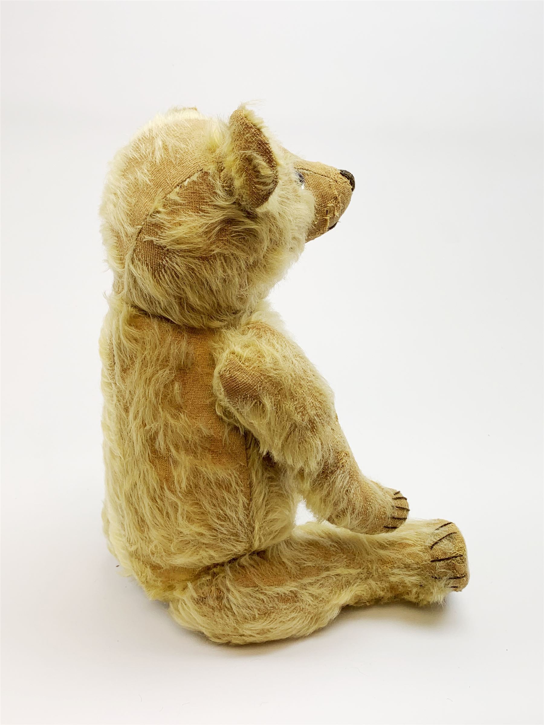 1930s teddy bear, possibly Farnell, with wood wool filled blond mohair body, the revolving head with original clear glass eyes, shaved muzzle with vertically stitched nose and mouth and jointed limbs with five-stitch claws H18.5