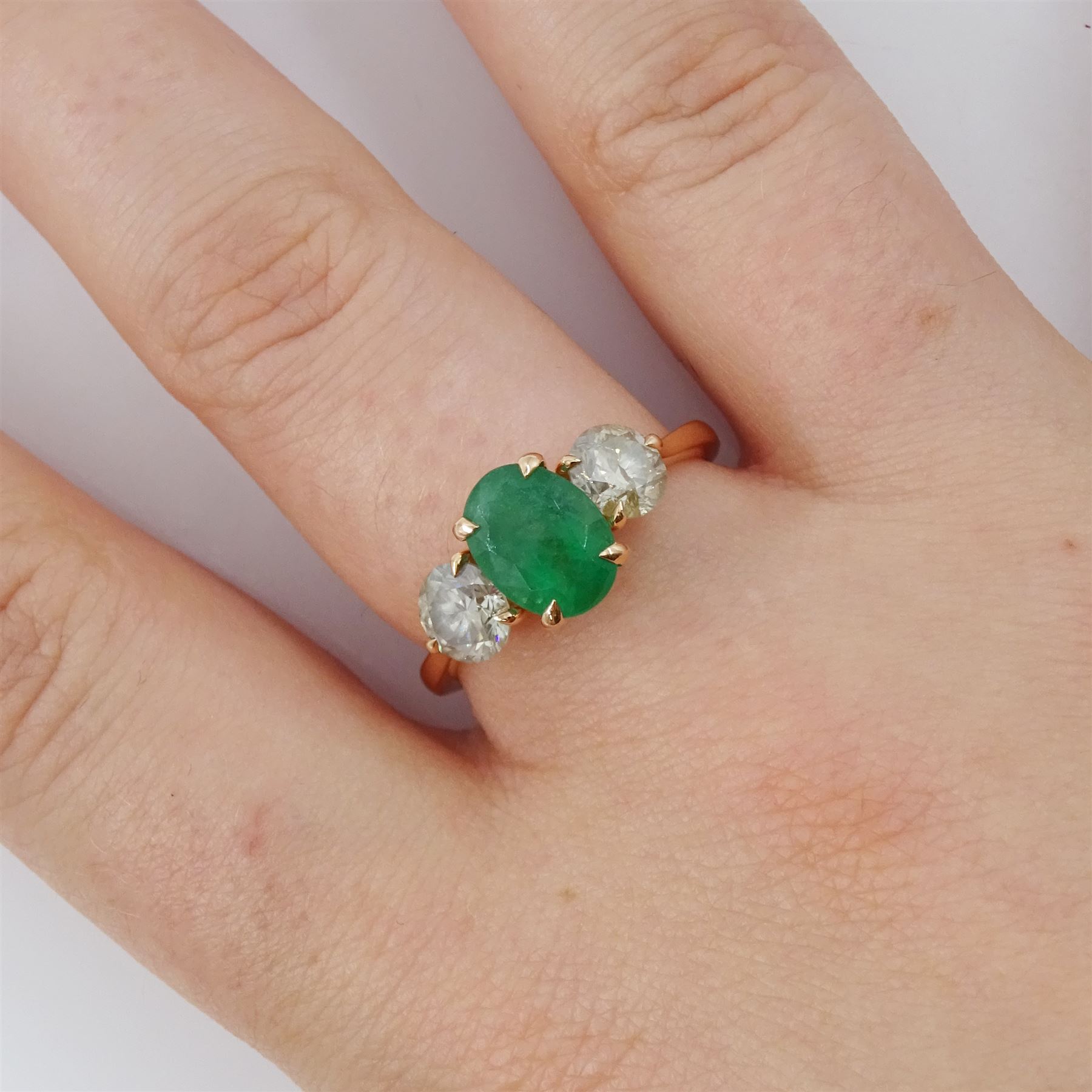 18ct rose gold three stone emerald and diamond ring, single oval cut emerald of approx 1.80 carat, with a round brilliant cut diamond set either side, hallmarked, total diamond weight approx 1.20 carat