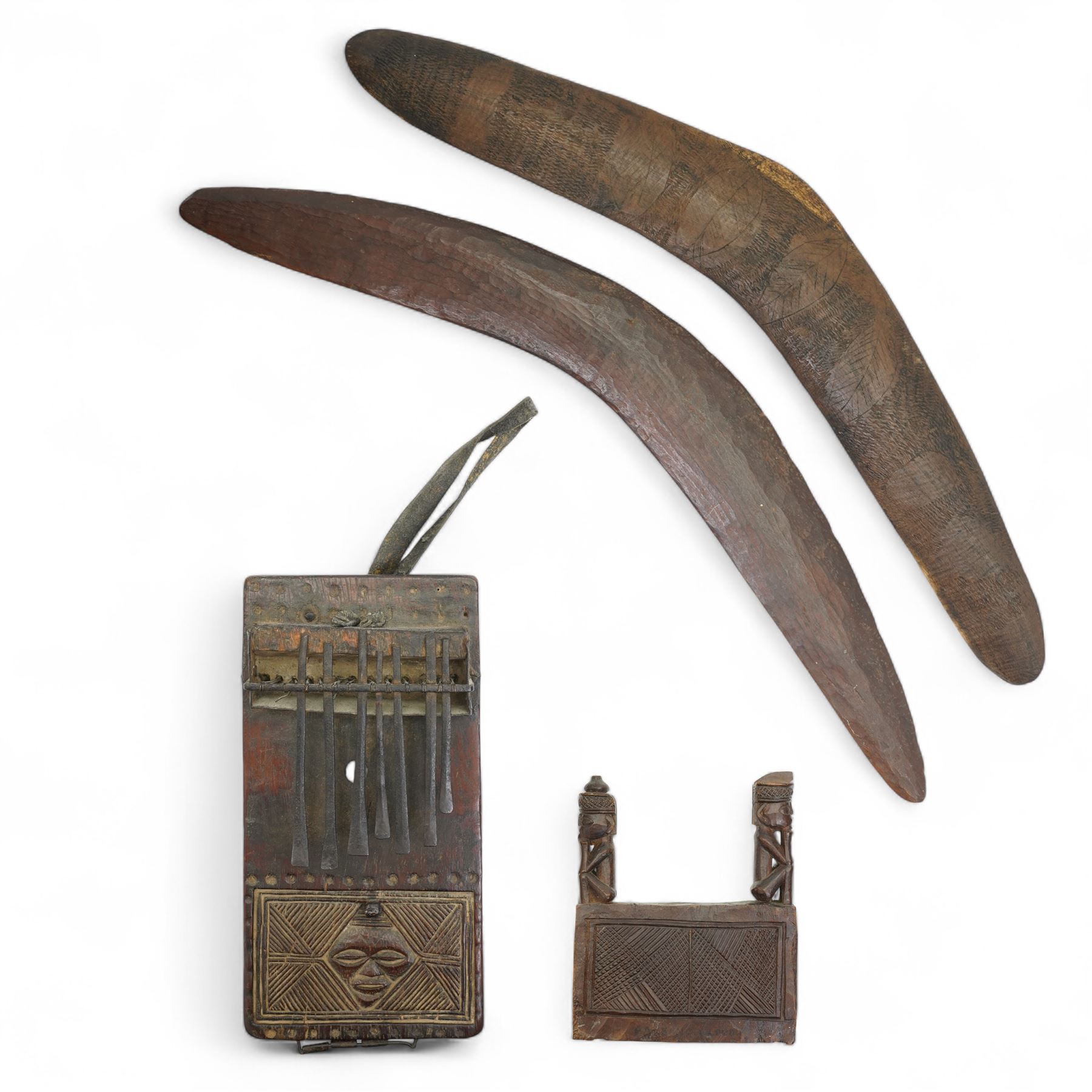 Australian Aboriginal boomerang decorated with eucalyptus leaves, a plain boomerang,  African wood and iron lamellophone and a carved wood tablet with two figures