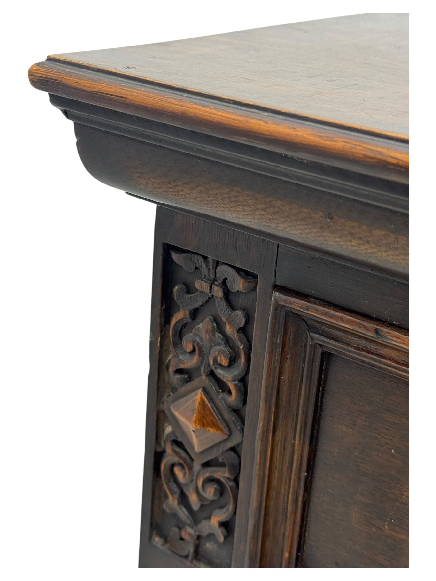 Jacobean-style oak dresser base with two frieze drawers above three cupboards with panelled and moulded decoration, fitted with drop handles, supported on bun feet, circa 1900
