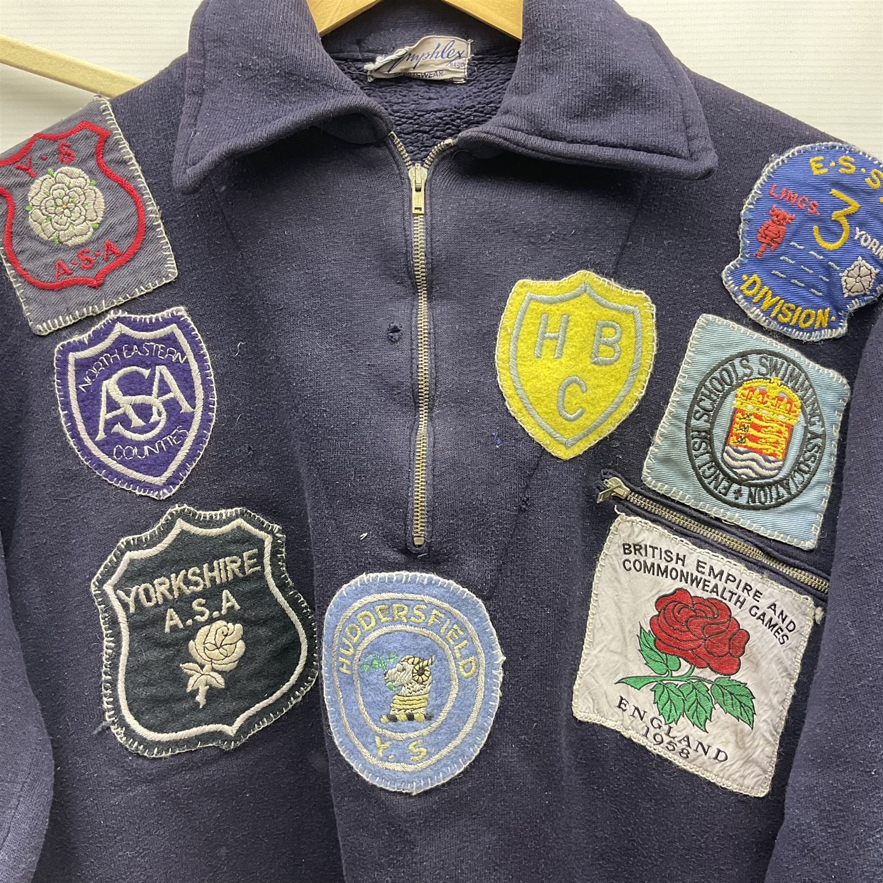 On the direct instructions of Anita Porter nee Lonsbrough Great British Olympic and Commonwealth Games gold medal winning swimmer - collection of early and international memorabilia comprising original Huddersfield Bath Club track suit top bearing eight stitched on cloth badges including British Empire & Commonwealth Games 1958 England Team, YSASA, North Eastern Counties ASA, ESSA Division 3,  English Schools Swimming Association winner etc
The swimming costume Anita wore at the 1958 Commonwealth Games in Cardiff, her first major championships, where she won two gold medals. The grey elastic on the sides, in those days, she would use to make it tighter and more streamlined.
Blue track suit from the 1960 Olympics which she wore on the podium receiving the gold medal.
1960 pool side towelling robe used at the Rome Olympics (interesting to note her name is spelt wrong on the embroidered label).
1962 Commonwealth Games pool side towelling robe used in Perth Australia when winning three Gold medals. 
It was also this year she became BBC Sports Personality of the year, the first female to do so.
Her 'lucky' pool side towel which she took with her to every event she competed in and which can be seen round her neck in many official celebratory photographs. Copies of some of these photographs are included for identification.
In addition there are two souvenir programmes of an evening event to honour Anita at The Theatre Royal Huddersfield and she has kindly signed the front cover on one of these.