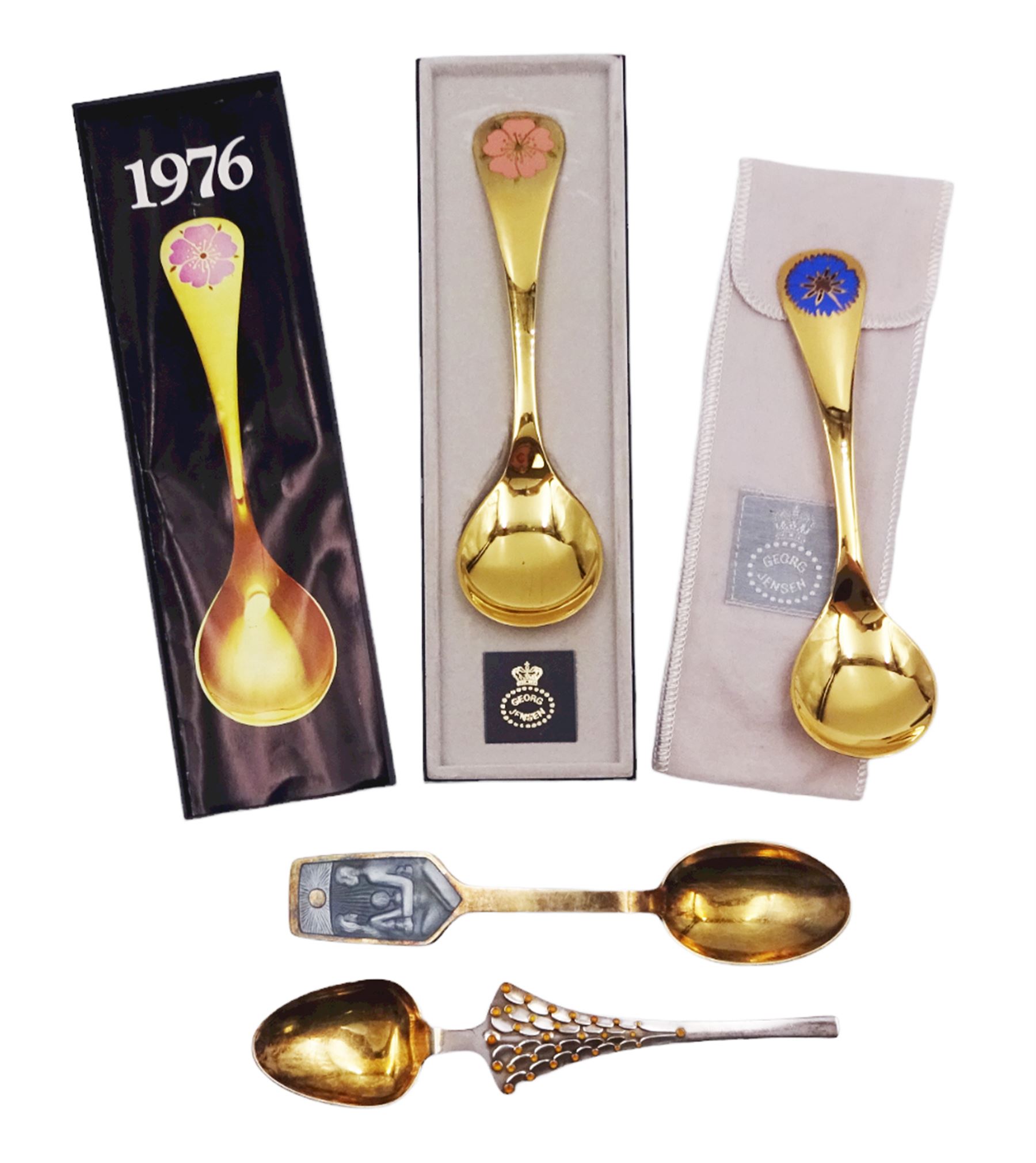 Two Danish silver-gilt year spoons by Georg Jensen, the first example decorated with enamel blue cornflower motif, dated 1972, in original pouch, the second example decorated with enamel pink briar rose motif, dated 1976, in original box, each impressed on underside RA AB, Sterling Denmark, and marked for Georg Jensen, together with two further examples by A.Michelson, the first with orange enamel fan design, dated 1965, impressed on underside A.Michelsen Sterling Danmark, TH, the second with enamel family scene, dated 1973, impressed on underside 925 S A.Michelsen Sterling Danmark, B Spang Olsen, approximate gross weight 6.11ozt (190.4 grams)