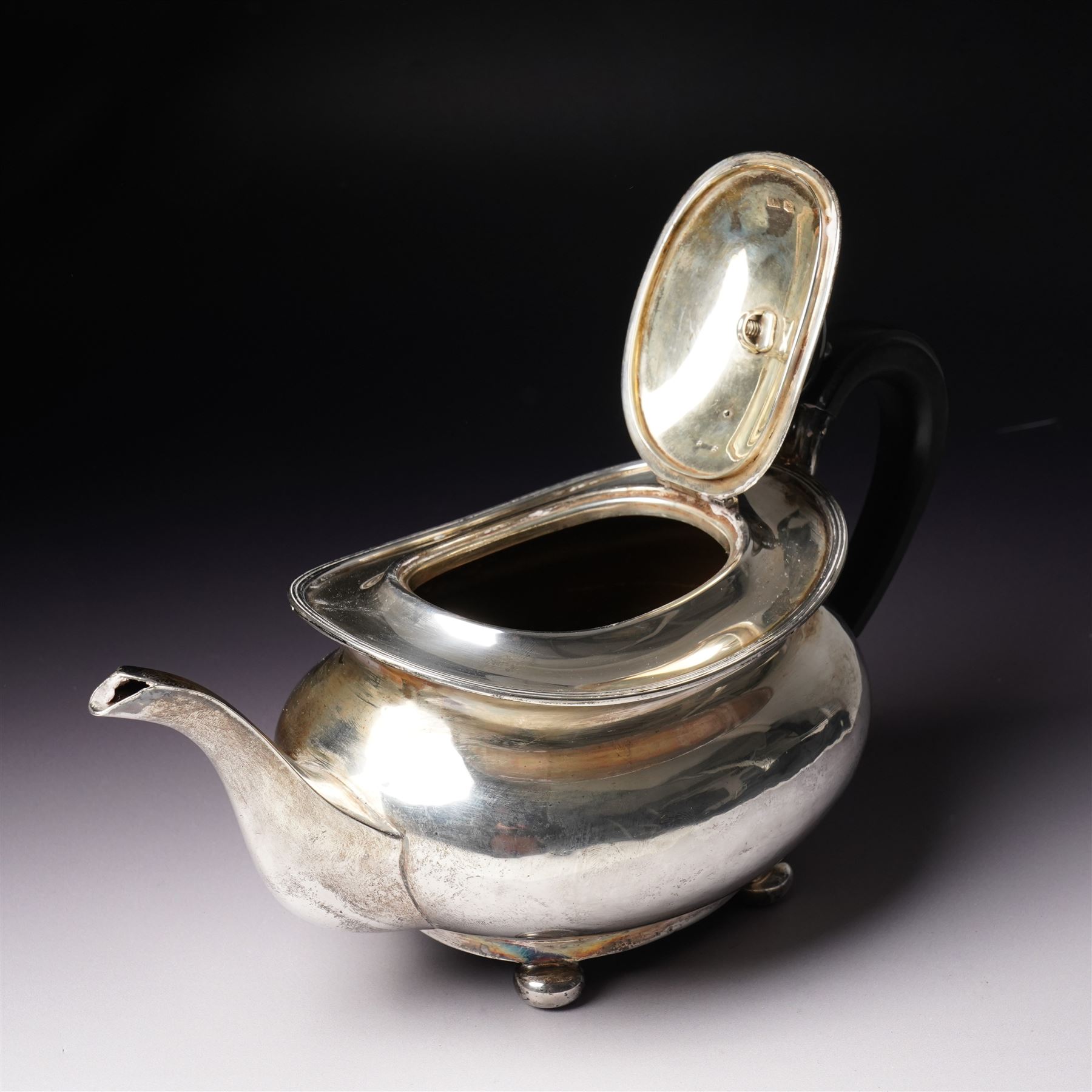 Silver tea pot of oval form with ebonised handle and lift on compressed bun feet Sheffield 1919 Maker Atkin Bros.