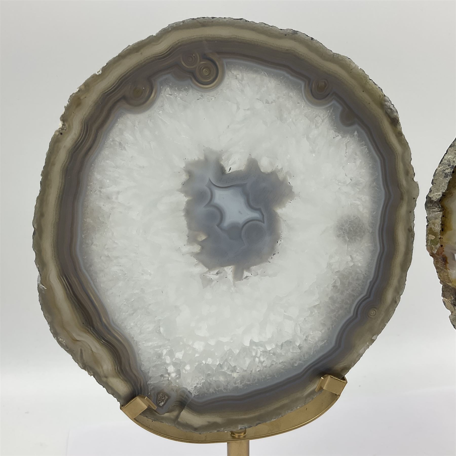 Pair of white agate slices, polished with rough edges raised upon gilt metal stands, H24cm