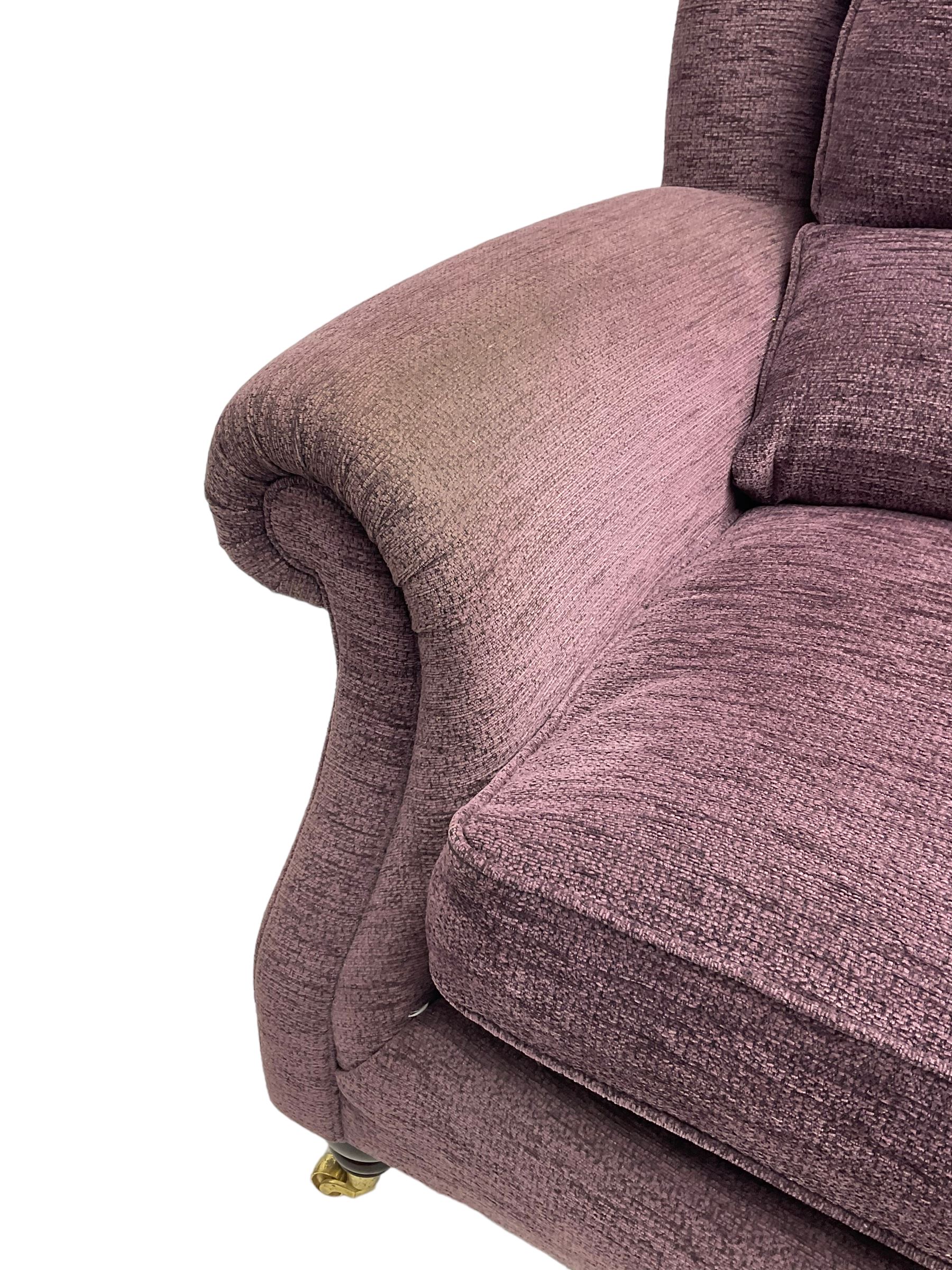 Parker Knoll - pair of large two-seat sofas upholstered in purple fabric, turned mahogany finish front feet with brass cups and castors 