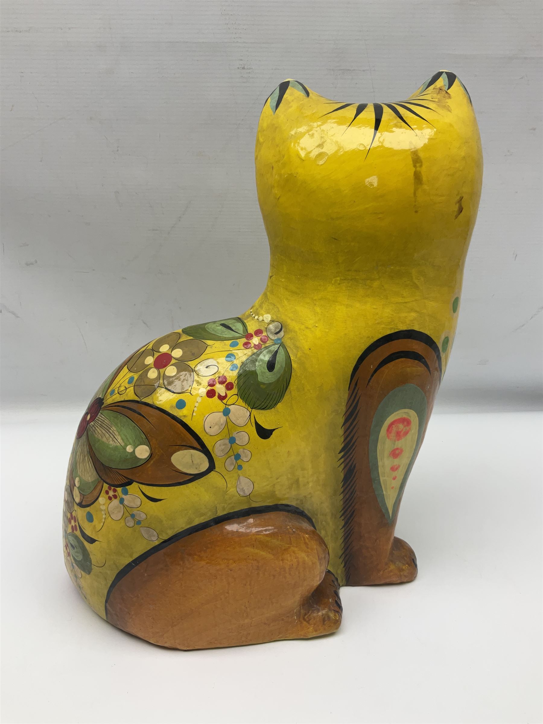 Papier mache model of a sitting cat, with painted floral and butterfly decoration, signed Serimel to base