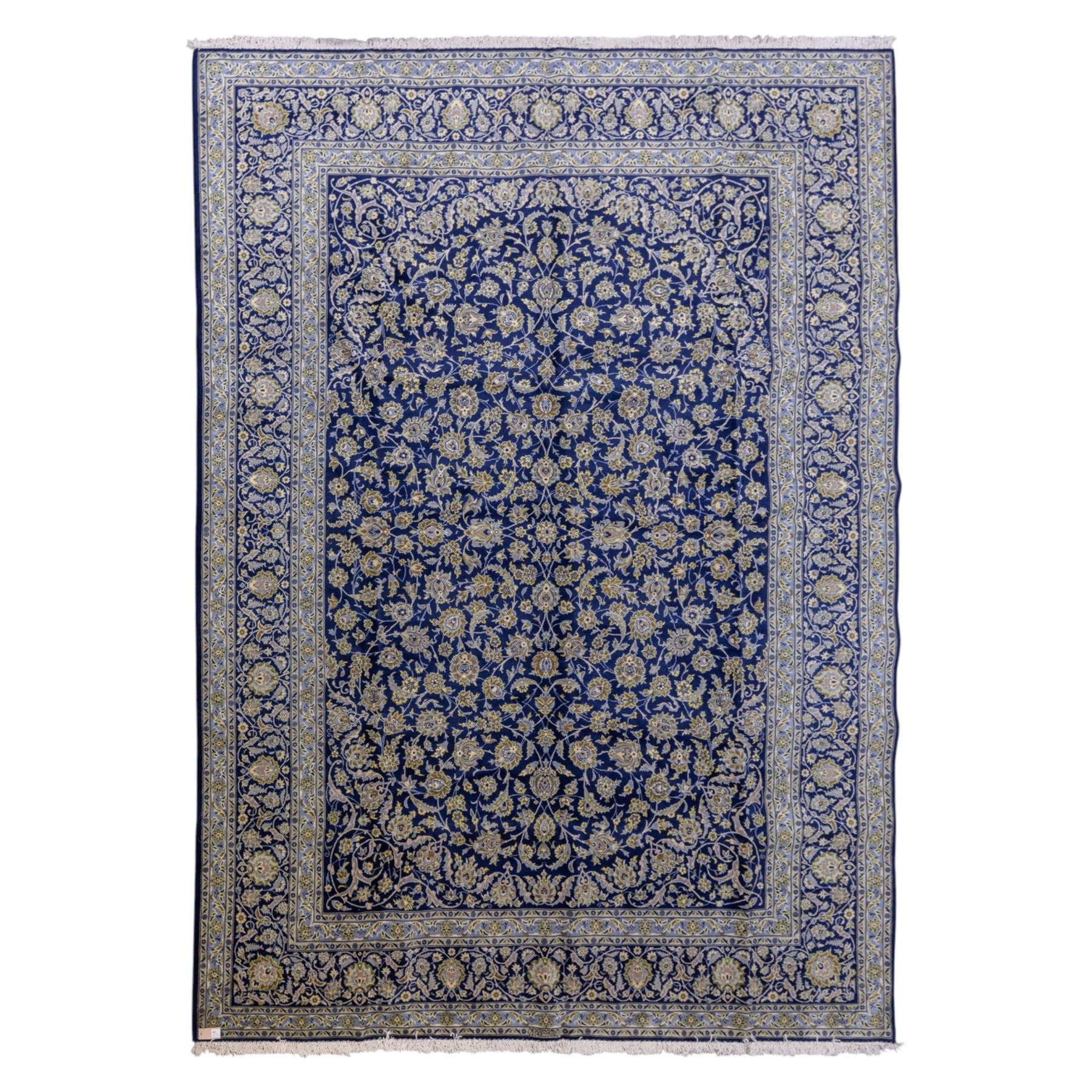 Central Persian Kashan hand-knotted rug, deep blue all-over field, finely decorated with dense scrolling floral sprays, palmettes, and flowering vines in ivory, soft gold, and pale green tones, enclosed by a multi-band floral border with corresponding guard stripes, with cotton fringe ends, signed Shah Abassi Workshop 