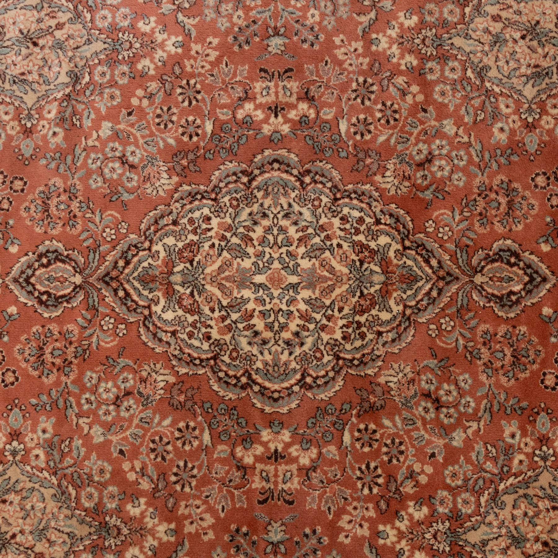 Persian vermillion ground Kashan rug, the busy field decorated with a central floral pole medallion, surrounded by trailing foliage and profusely woven floral patterns and bouquets, the dark indigo spandrels and multiple guard bands with similar floral decoration and stylised spandrels
