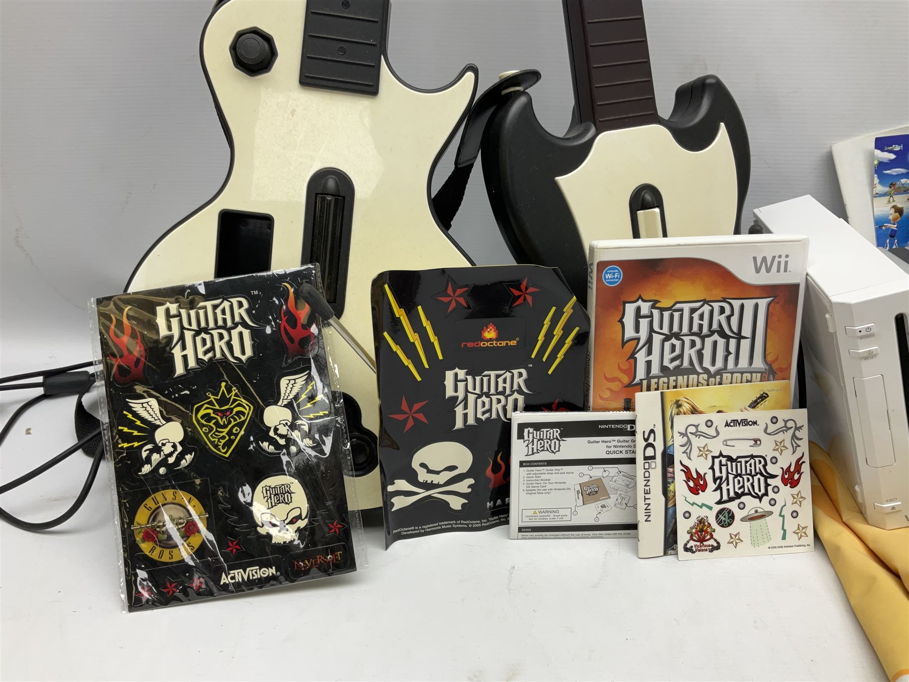 Nintendo Wii console, four controllers with cases and four nunchucks, Wii sensor bar, balance board and dance mat. Guitar hero wireless guitar for Wii and Redoctane wired guitar. Nintendo DS lite handheld gaming console, console and game cases and Guitar Hero Redoctane Guitar Grip. Selection of Nintendo Wii and Nintendo DS lite games to include Super Mario Galaxy, Guitar Hero, Wii Fit, Legend of Zelda games etc. Archos AV400 Series pocket video recorder with accessories, cradle and remote, in three boxes