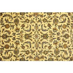 Central Persian Kashan carpet, ivory ground, field with an all-over design of scrolling palmettes and floral sprays in blue and terracotta within a beige ground and pale blue floral border