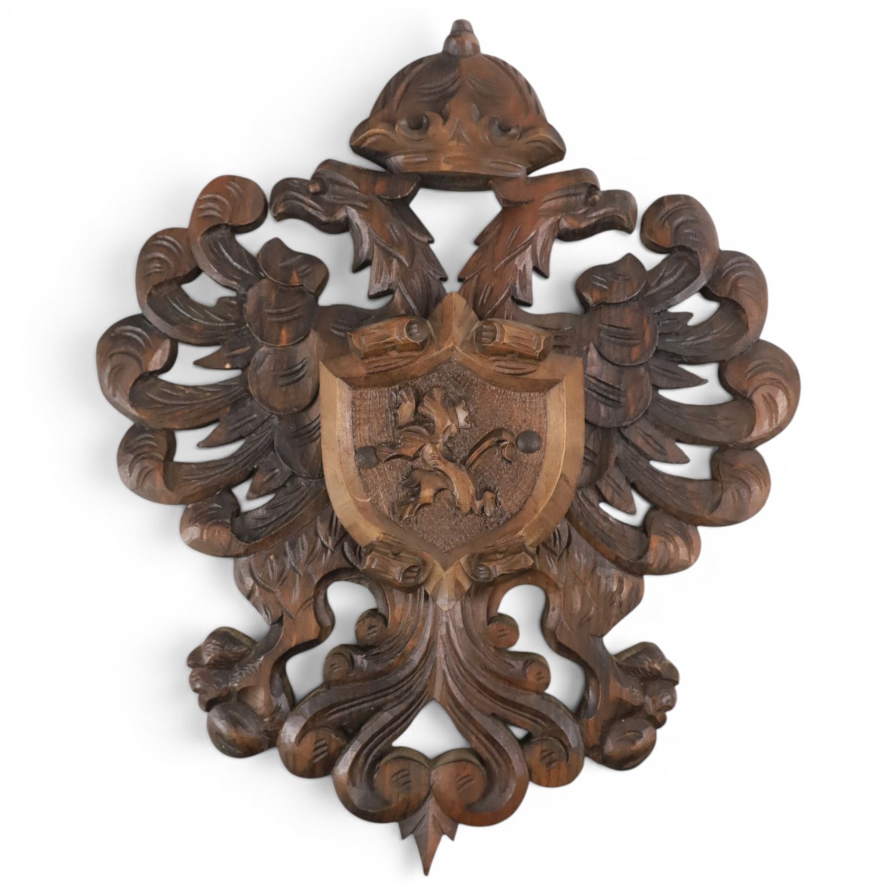 Carved wooden wall plaque, decorated with foliate scrolls, with two reproduction swords attached, together with five other wooden plaques with foliate scrolls and shields