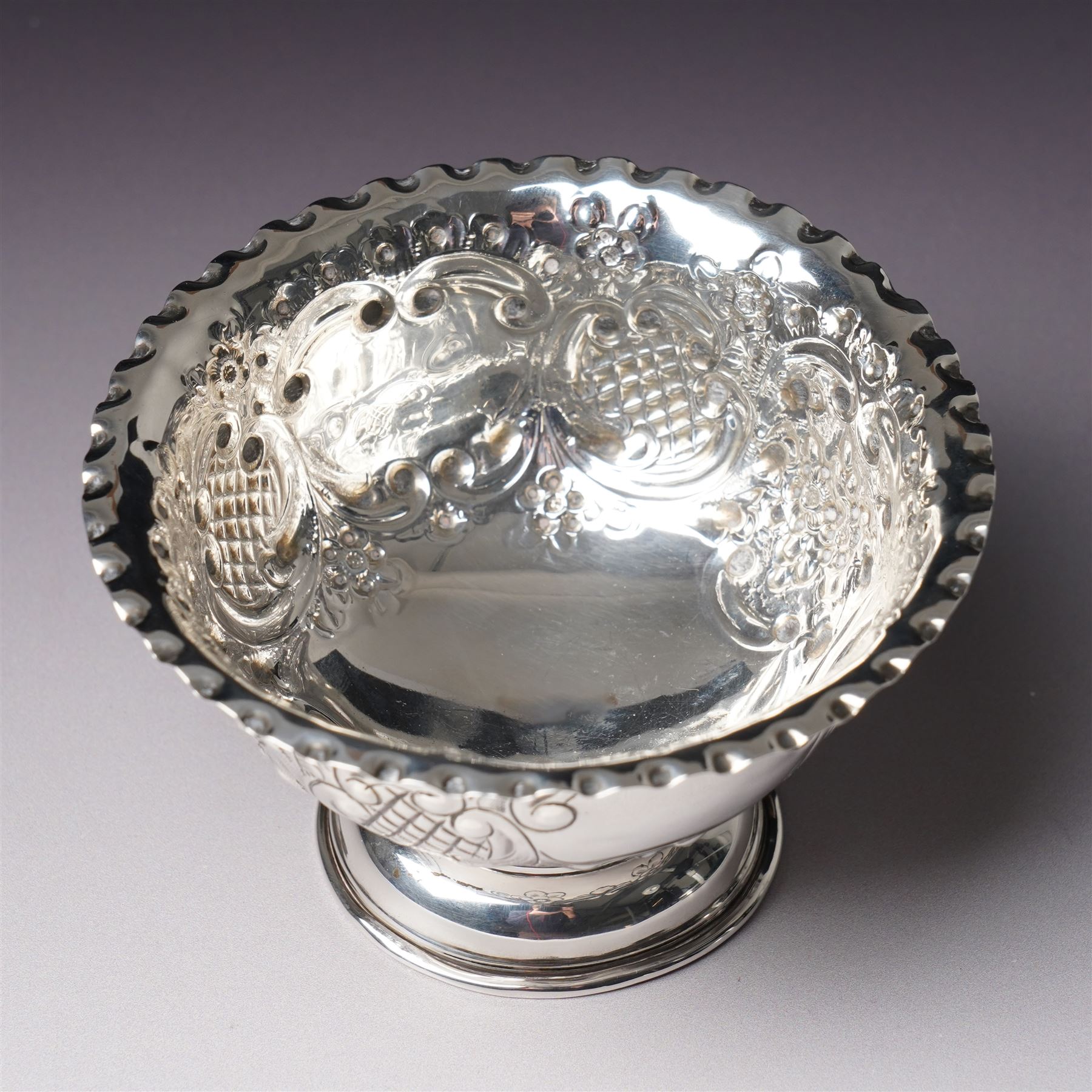 Edwardian silver bowl with embossed decoration on a short pedestal foot D11cm Birmingham 1904 Maker A & J Zimmerman Ltd and a modern silver coaster with turned wooden base D9.5cm Sheffield 2001 (2)