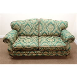 Traditional two seat sofa, scrolled arms, turned supports on brass castors, upholstered  in green and gold fabric with a floral pattern, W187cm  