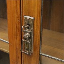 20th century wooden bookcase cabinet, fitted with a pair of leaded glass panel doors opening to adjustable shelves, the base top and front veneered in richly figured walnut, contrasted with solid oak panelled sides and shaped lower frieze, terminating in castors