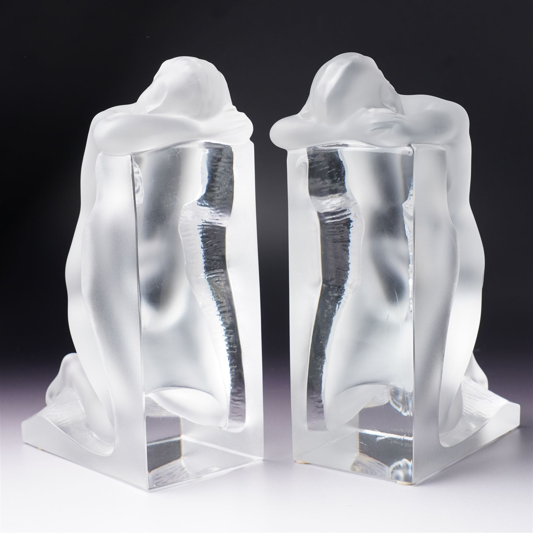 Pair of Lalique 'Reverie' glass bookends formed as two kneeling nude figures in clear and frosted glass inscribed 'Lalique France' to the plinth base H23cm