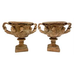 Pair of late 19th/early 20th century terracotta twin handled campagna urns or Warwick vases, decorated in relief with a band of classical male and female masks, above a lower band of lion masks, the handles modelled as twisted vines leading to a fruiting vine beneath a beaded and lobed rim, H29cm