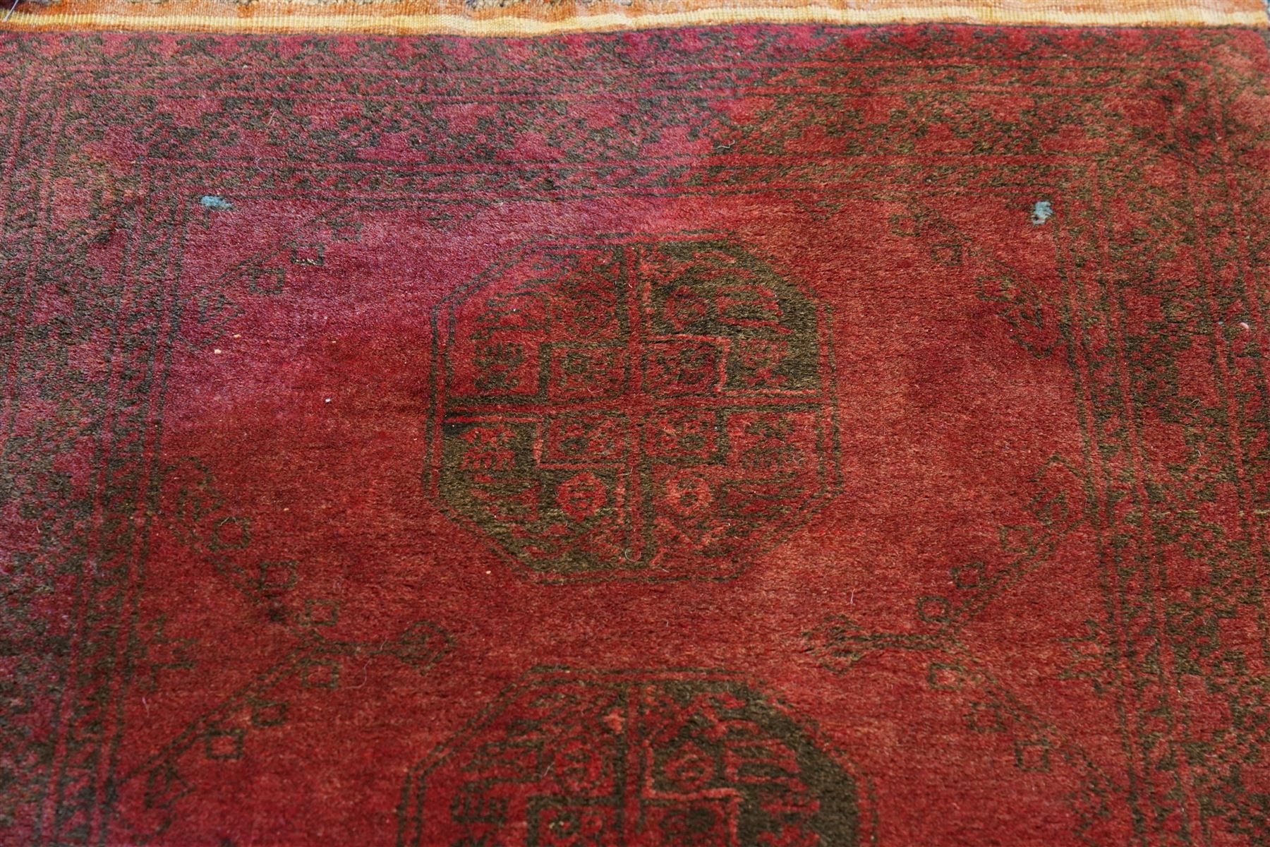 Antique Persian Bokhara red ground runner rug, repeating Gul pattern, surrounded by borders, with fringed ends