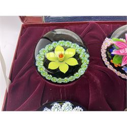Set of four Caithness paperweights titled Four Seasons, in presentation box with certificate, designed by Colin Terris and made by William Mason, each internally decorated with a seasonal flower within a millefiori cane work garland, numbered 128 of 500