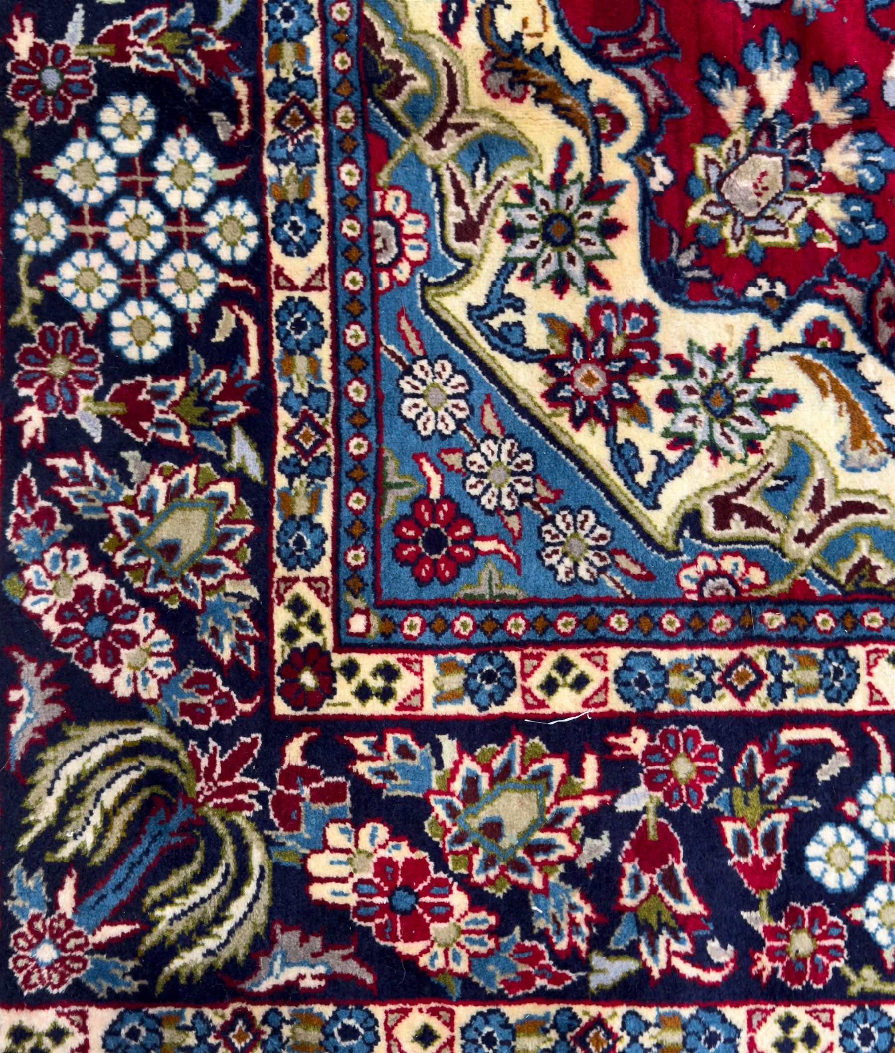 Central Persian Isfahan Carpet, hand-knotted, featuring a bold central rosette medallion on a rich red field, flanked by stylised floral sprays, scrolling foliage and mythical animals, within a broad indigo border decorated with alternating cartouches and flowerheads