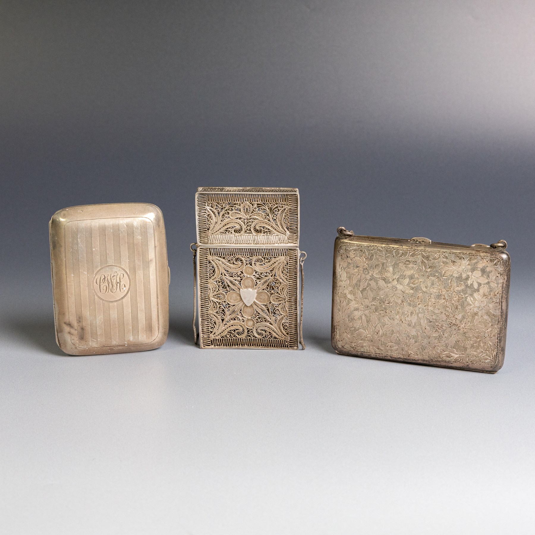 Early 20th century silver coin purse, with floral decoration and finger chain, hallmarked together with an early 20th century cigarette case,  with engraved initials, hallmarked and a silver filigree cigarette case