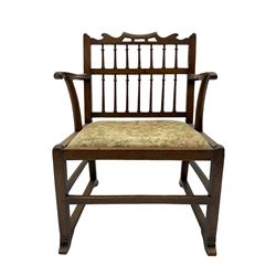 Late 18th century walnut 'Drunkard's' chair, the shaped cresting rail over spindle back, wide set seat with upholstered drop in cushion, shaped arms with scroll carved terminals, sledge supports with bracket feet joined by plain stretchers 