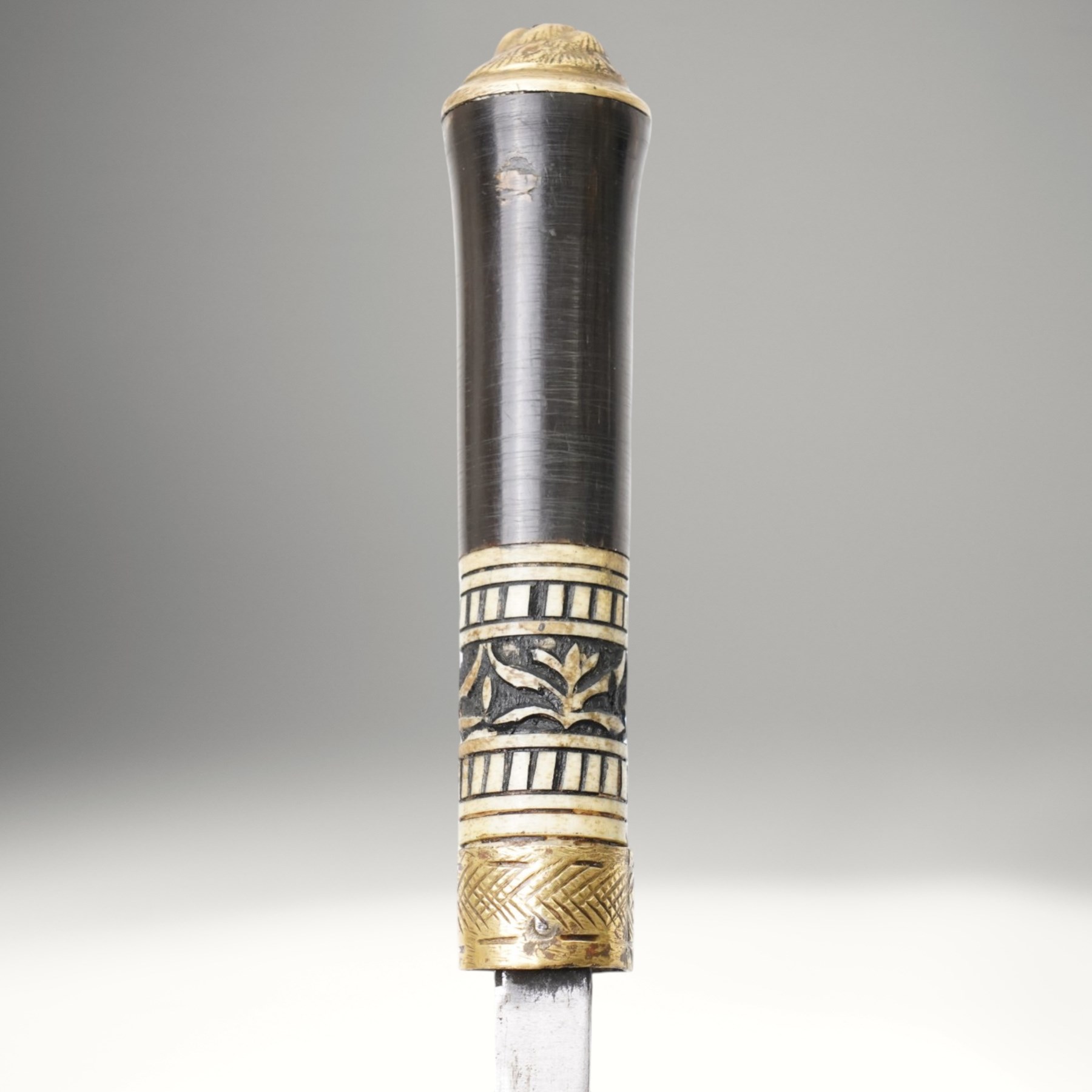 Early 20th century Indian concealed sword-stick, the black wooden scabbard and grip with carved bone collar, engraved brass band, and brass pommel in the form of a tigers head, W92cm