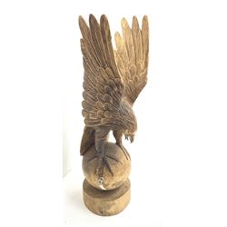 A carved carved wooden figure, modelled as an eagle upon a sphere and circular base, overall H105.5cm. 