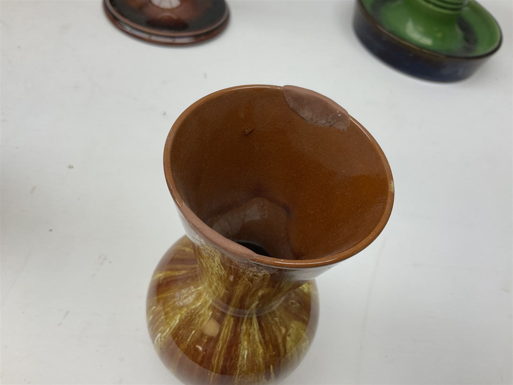 Linthorpe pottery vase with crimped rim and ovoid body, Linthorpe jug with high loop handle and crimped spout, a pair of candlesticks with a green, brown glaze and other similar pottery 