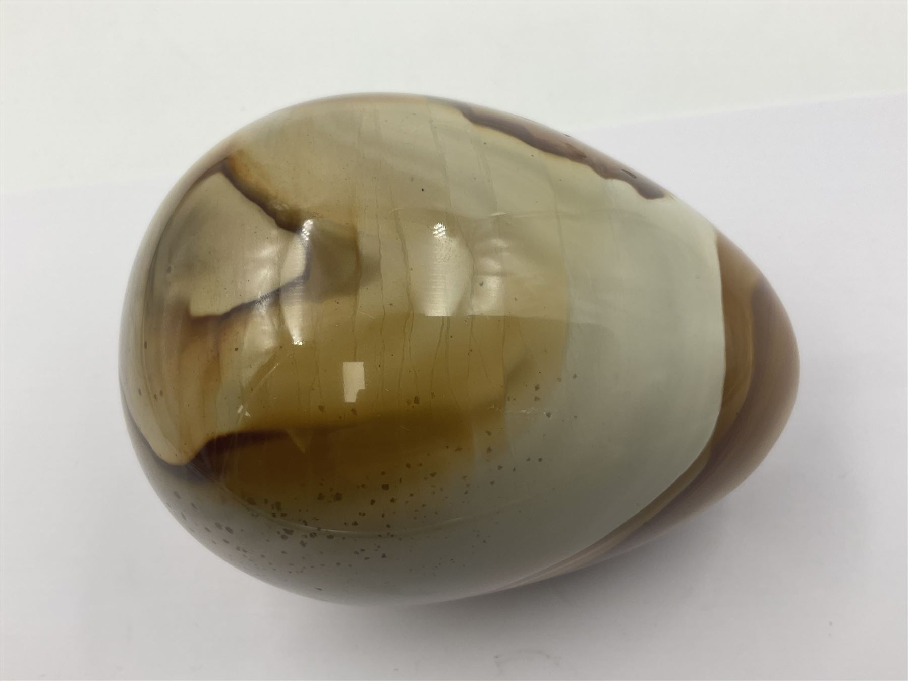 Polychrome jasper specimen egg, in creams, browns and earthy tones, upon a wooden stand, H12cm