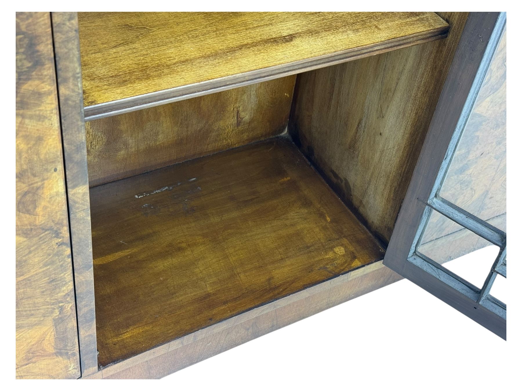Art Deco burr walnut drinks cabinet, geometric central glazed astragal door enclosing two fixed shelves, flanked by symmetrical bookmatched veneered cupboards with drawers above 