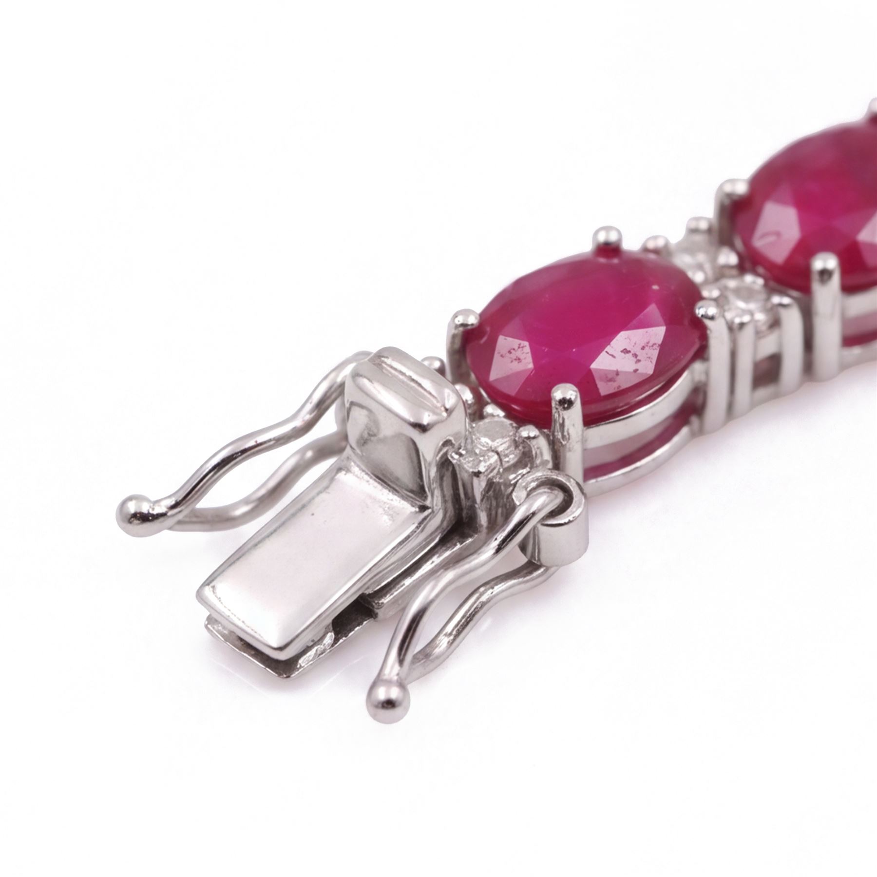 18ct white gold ruby and diamond bracelet, twenty-six oval cut rubies, each spaced by two round brilliant cut diamonds, stamped 750, total ruby weight 12.70 carat, total diamond weight 0.46 carat