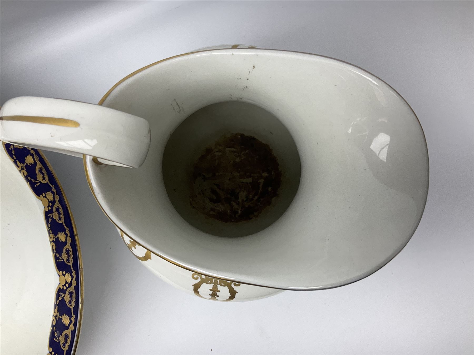 Early 20th century Bishop and Stonier four piece toilet set, comprising washbowl, wash jug, toothbrush pot, and chamber pot, each  decorated with deep blue band and husk swags and festoons in gilt, with printed Caduceus Bisto marks beneath and printed retailers mark 'Manufactured for Harrods Limited London', wash bowl D43cm, wash jug H31.5cm