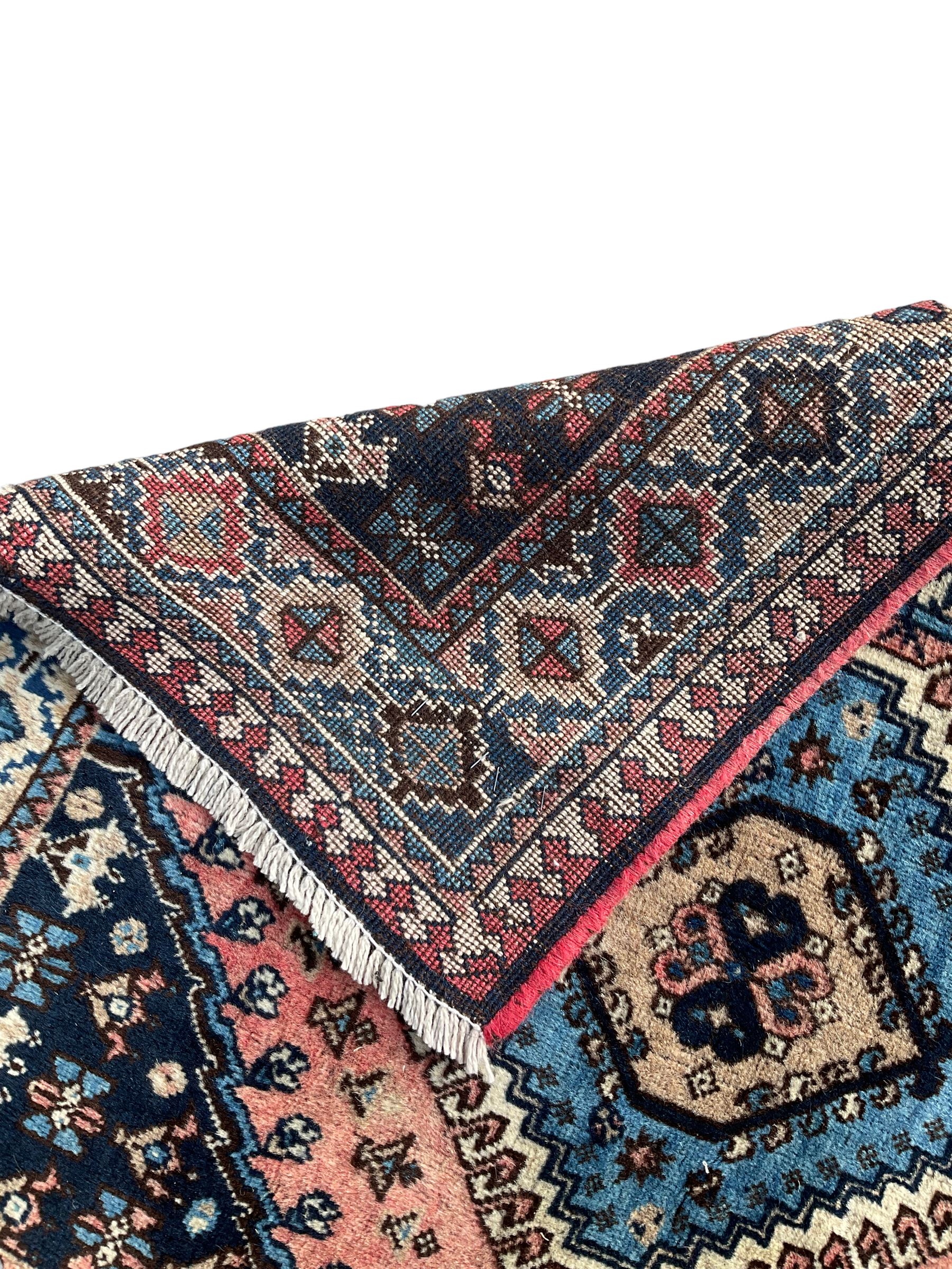 Persian Yalameh coral ground runner rug, the field decorated with seven hooked lozenge medallions surrounded by stylised plant motifs, the indigo spandrels decorated with similar patterns, guarded border with repeating diamond lozenges